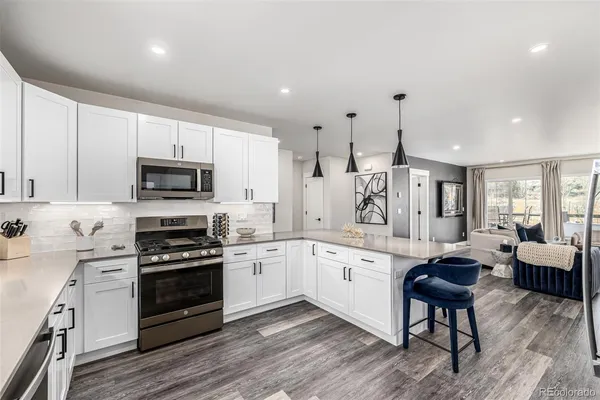 a large kitchen with stainless steel appliances granite countertop a stove a sink dishwasher a dining table and chairs with wooden floor