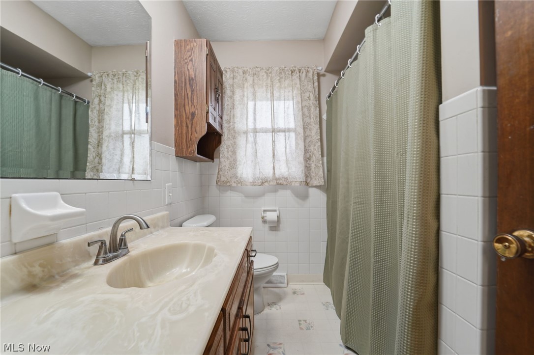 14557 Ellsworth Road Berlin Center, OH 44401 - Photo 17 of 23 Full bathroom featuring vanity, a shower with curtain, a textured ceiling, and tile walls