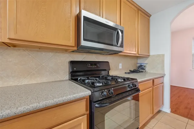 a kitchen with stainless steel appliances granite countertop white cabinets and a stove top oven
