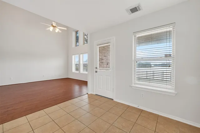 a view of an empty room with a window and wooden floor