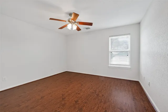 an empty room with wooden floor and ceiling fan