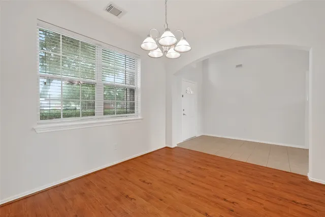 a view of empty room with wooden floor and chandelier
