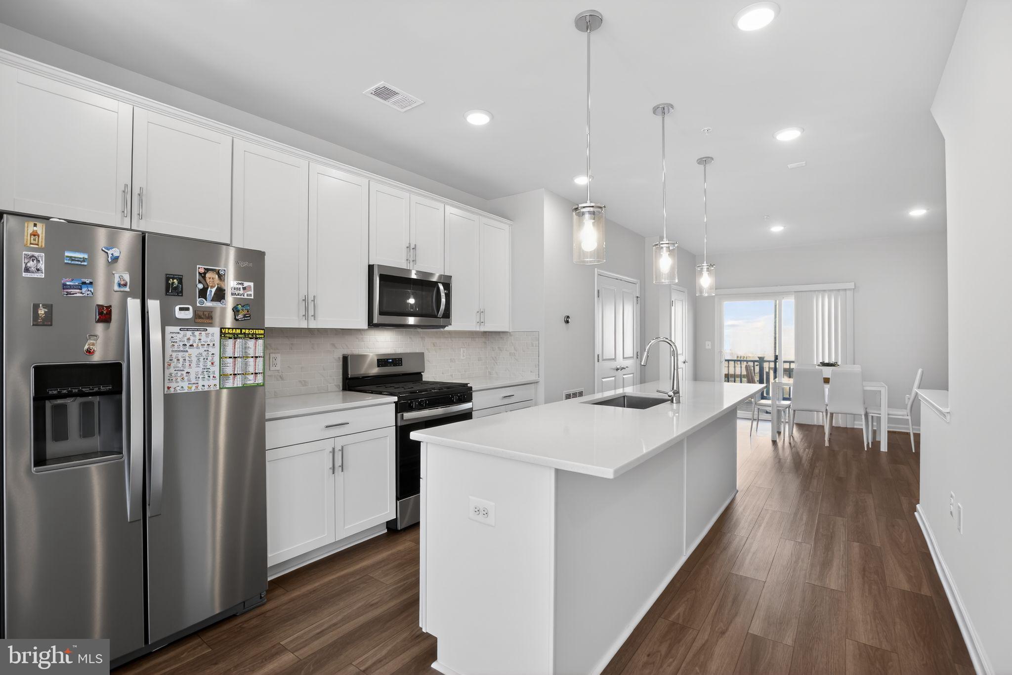 299 Freshet Lane Laurel, MD 20724 - Photo 20 of 33 a kitchen with stainless steel appliances kitchen island granite countertop a stove a sink a refrigerator and white cabinets with wooden floor