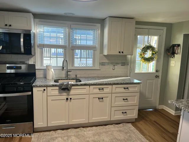 a kitchen with granite countertop a sink stainless steel appliances and cabinets