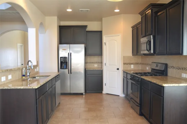 a kitchen with stainless steel appliances granite countertop a refrigerator a sink and a stove