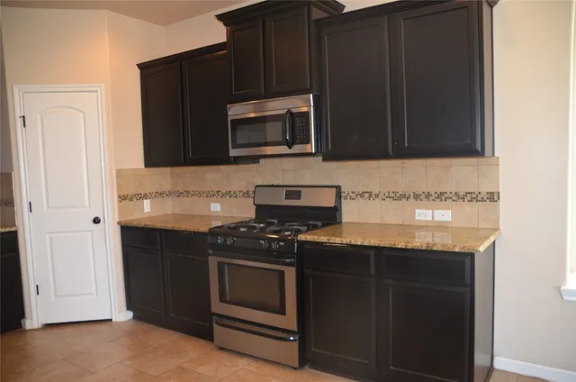 a kitchen with granite countertop a stove and a microwave