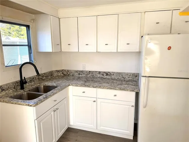a kitchen with granite countertop white cabinets and a sink