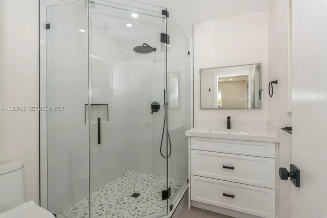 a bathroom with a shower sink vanity and mirror