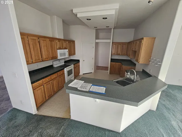 a kitchen with granite countertop a sink a stove and cabinets