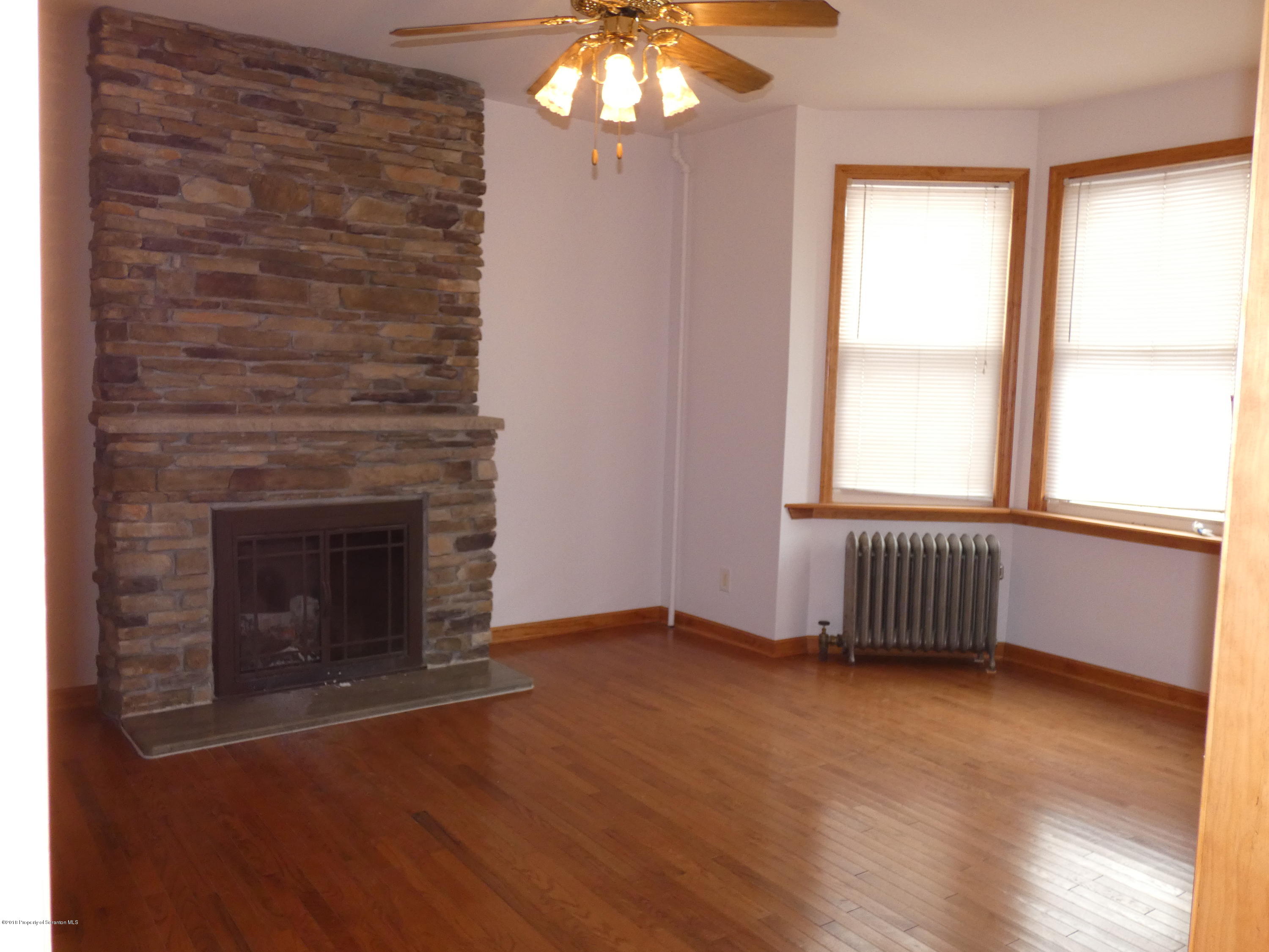 613 Fig Street Scranton, PA 18505 - Photo 9 of 36 an empty room with wooden floor a fireplace and windows