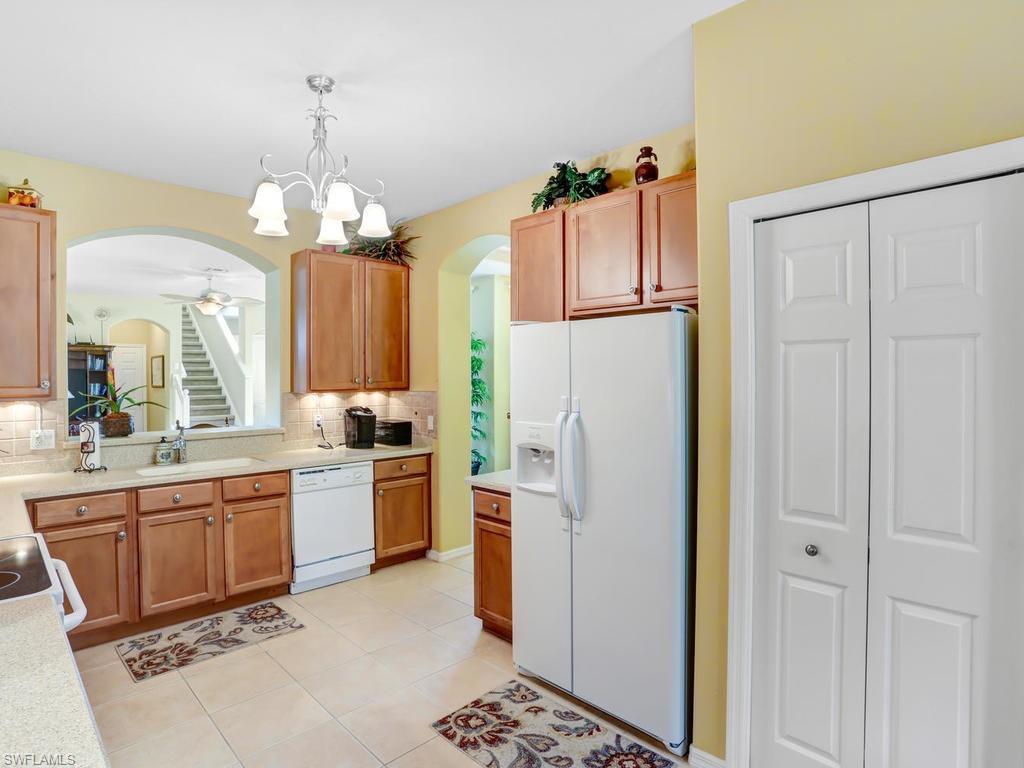 5786 Lago Villaggio Way Naples, FL 34104 - Photo 13 of 29 a kitchen with stainless steel appliances granite countertop a refrigerator a oven a sink and a chandelier