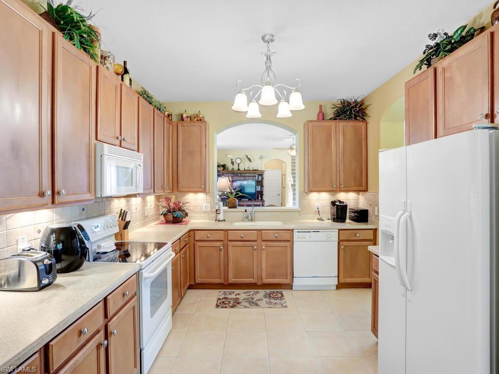 5786 Lago Villaggio Way Naples, FL 34104 - Photo 14 of 29 a kitchen with lot of cabinets and refrigerator