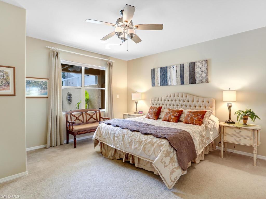 5786 Lago Villaggio Way Naples, FL 34104 - Photo 16 of 29 a bedroom with a bed and a chandelier