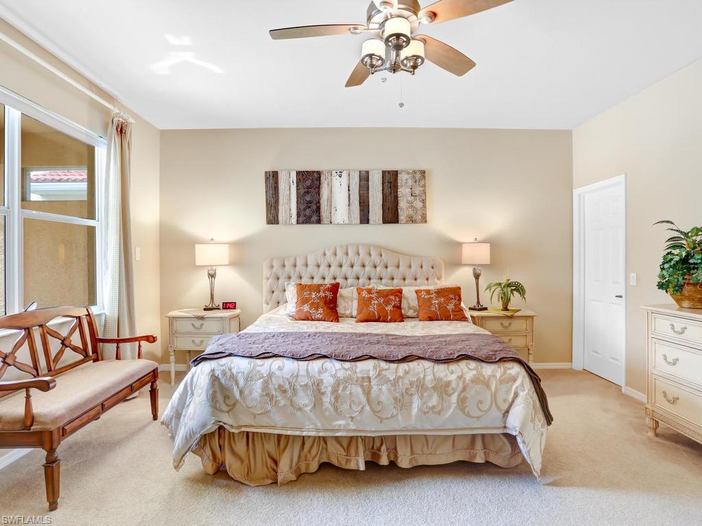 5786 Lago Villaggio Way Naples, FL 34104 - Photo 17 of 29 a bedroom with a bed and a chandelier