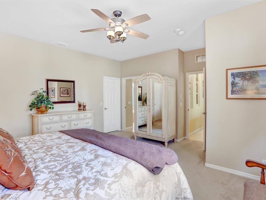 5786 Lago Villaggio Way Naples, FL 34104 - Photo 18 of 29 a spacious bedroom with a bed and a chandelier