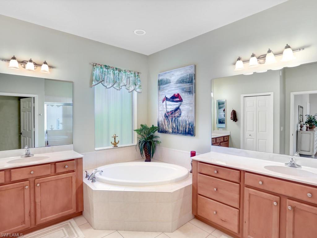 5786 Lago Villaggio Way Naples, FL 34104 - Photo 19 of 29 a spacious bathroom with a double vanity sink a mirror a and a shower
