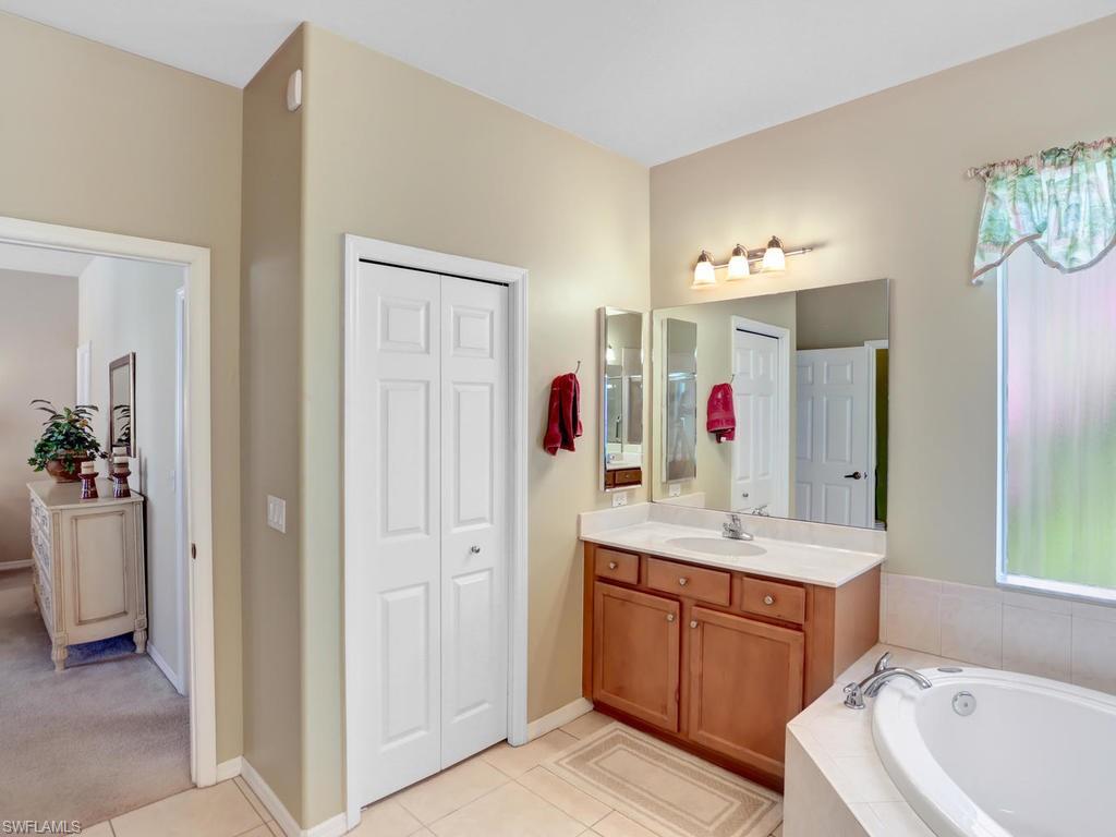 5786 Lago Villaggio Way Naples, FL 34104 - Photo 20 of 29 a bathroom with a tub sink and mirror