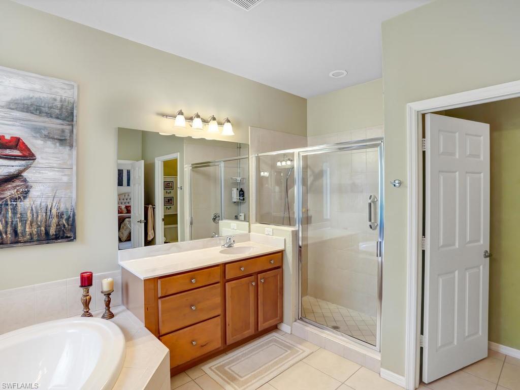 5786 Lago Villaggio Way Naples, FL 34104 - Photo 21 of 29 a bathroom with a double vanity sink mirror and shower