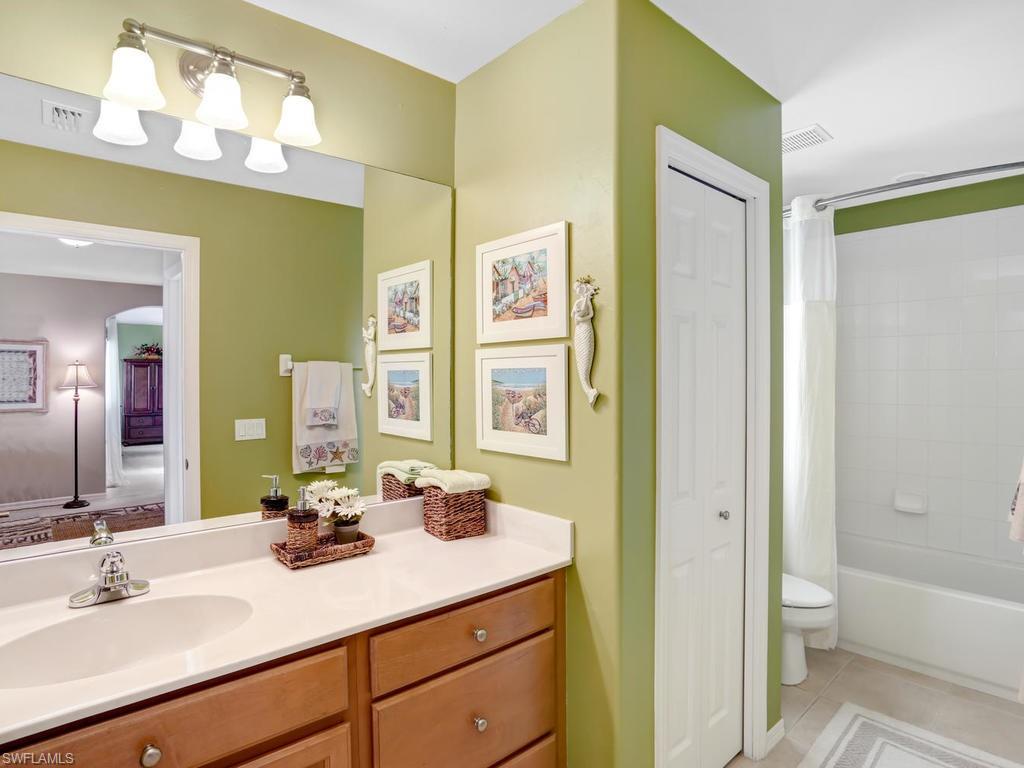5786 Lago Villaggio Way Naples, FL 34104 - Photo 24 of 29 a bathroom with a granite countertop sink mirror and a bathtub