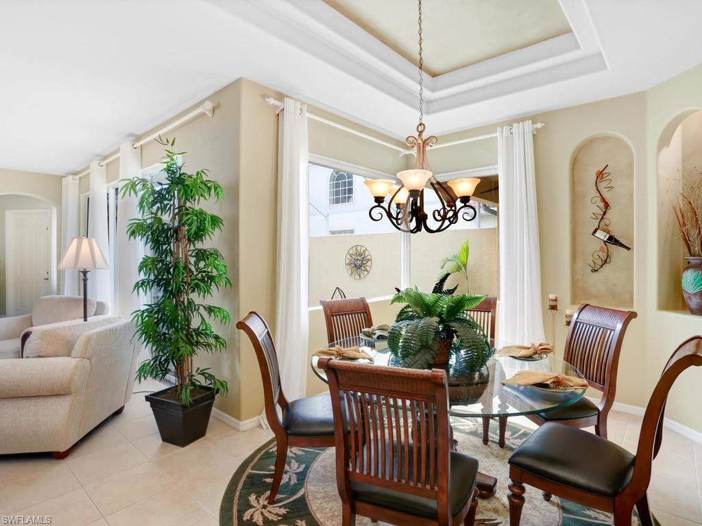 5786 Lago Villaggio Way Naples, FL 34104 - Photo 9 of 29 a dining room with furniture potted plants and wooden floor