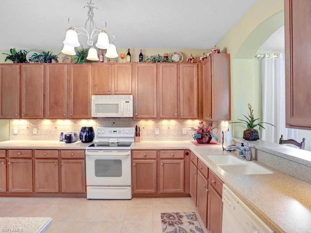 5786 Lago Villaggio Way Naples, FL 34104 - Photo 10 of 29 a kitchen with a sink stove and cabinets