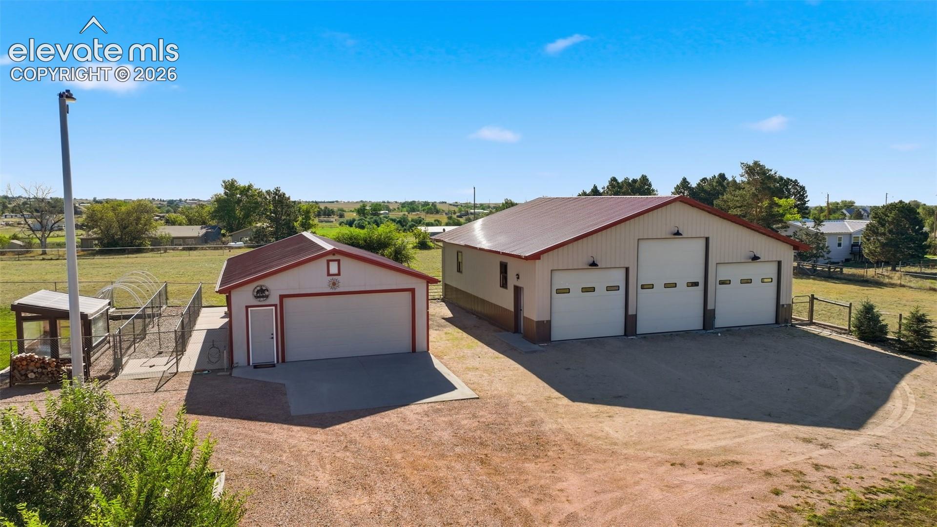 6015 West Condor Road Peyton, CO 80831 - Photo 45 of 50 Large outbuilding featuring three garage doors and exterior lighting