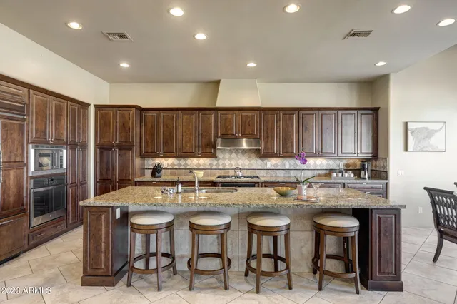 a kitchen with stainless steel appliances granite countertop a table chairs sink refrigerator and cabinets