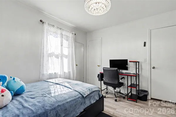 a bedroom with a bed table chair and a window