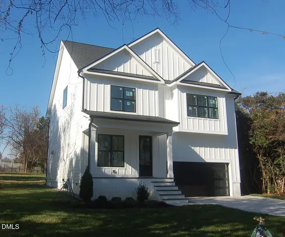 a front view of a house with a garden and trees