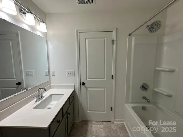 a bathroom with a tub sink double vanity granite tub shower and mirror