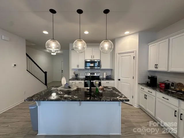 a kitchen with granite countertop a sink a stove and cabinets