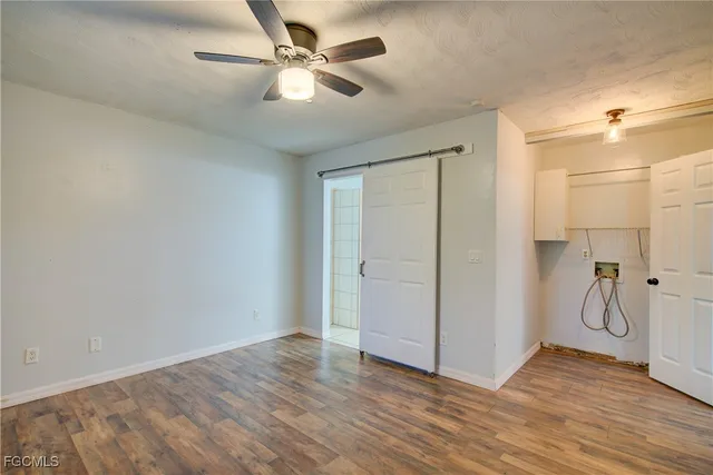 a view of an empty room with wooden floor and a ceiling fan