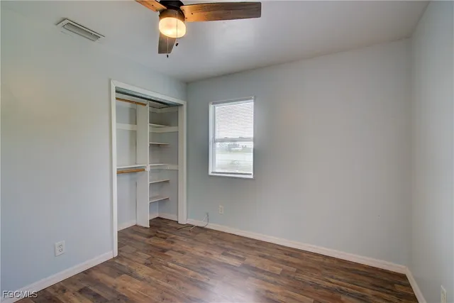 an empty room with wooden floor closet and windows