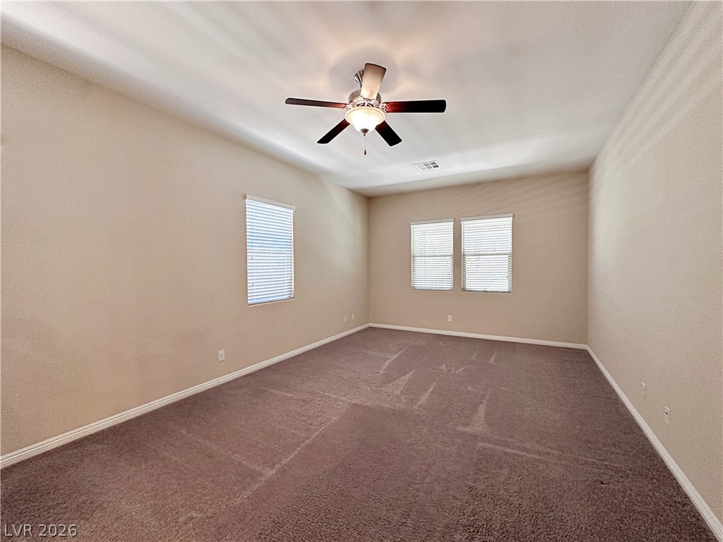 71 Newton Ridge Way Las Vegas, NV 89183 - Photo 26 of 40 A spacious, naturally illuminated room features plush carpeting and a modern ceiling fan.