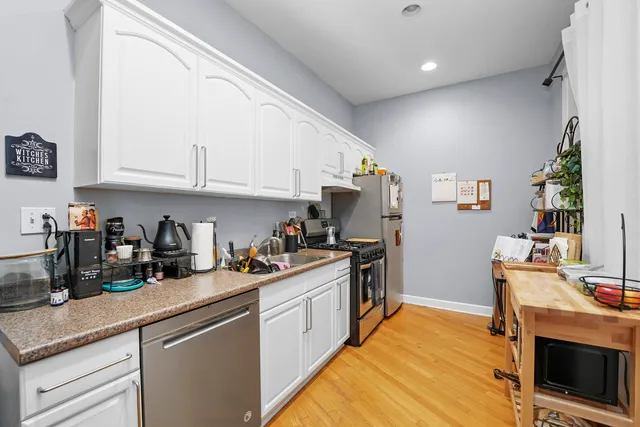 a kitchen with stainless steel appliances granite countertop a stove a sink dishwasher and a refrigerator with wooden floor