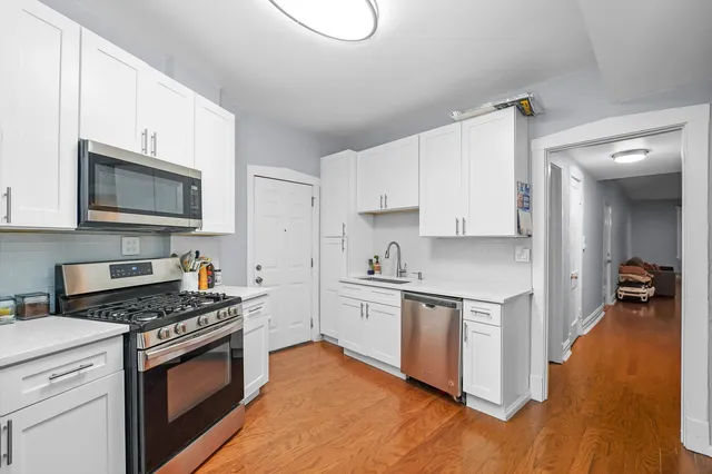 a kitchen with cabinets stainless steel appliances and wooden floor