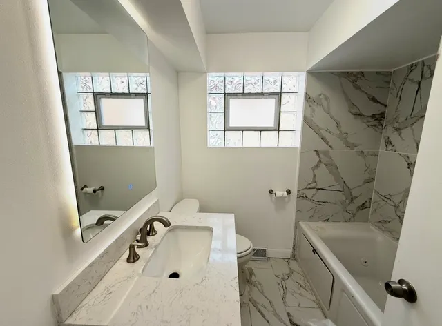 a bathroom with a tub sink and mirror