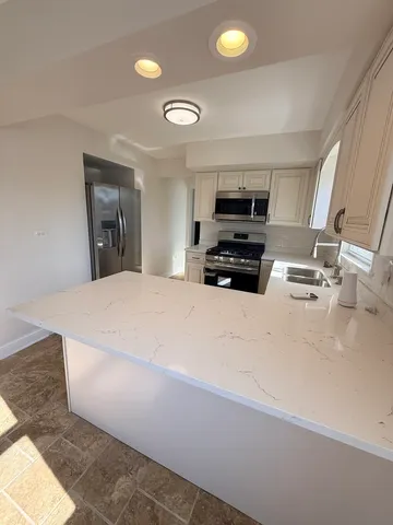 a kitchen with kitchen island a sink stainless steel appliances and cabinets