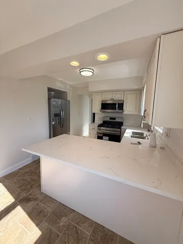 a large white kitchen with a sink and a fireplace