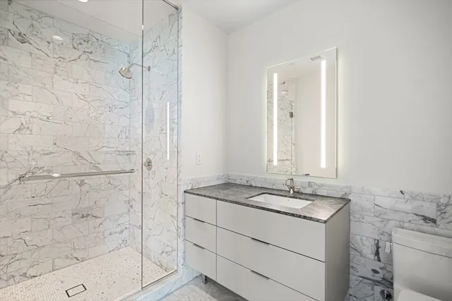 a bathroom with a granite countertop sink a mirror and a shower
