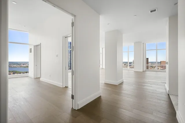 a view of a hallway with wooden floor and a living room