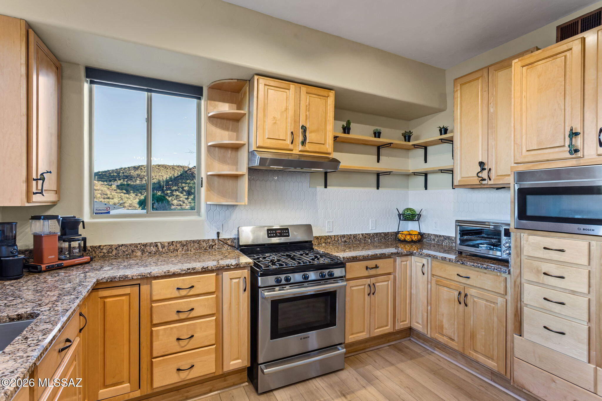 4210 West Mossman Road Tucson, AZ 85746 - Photo 5 of 51 a kitchen with granite countertop a stove a sink and wooden cabinets