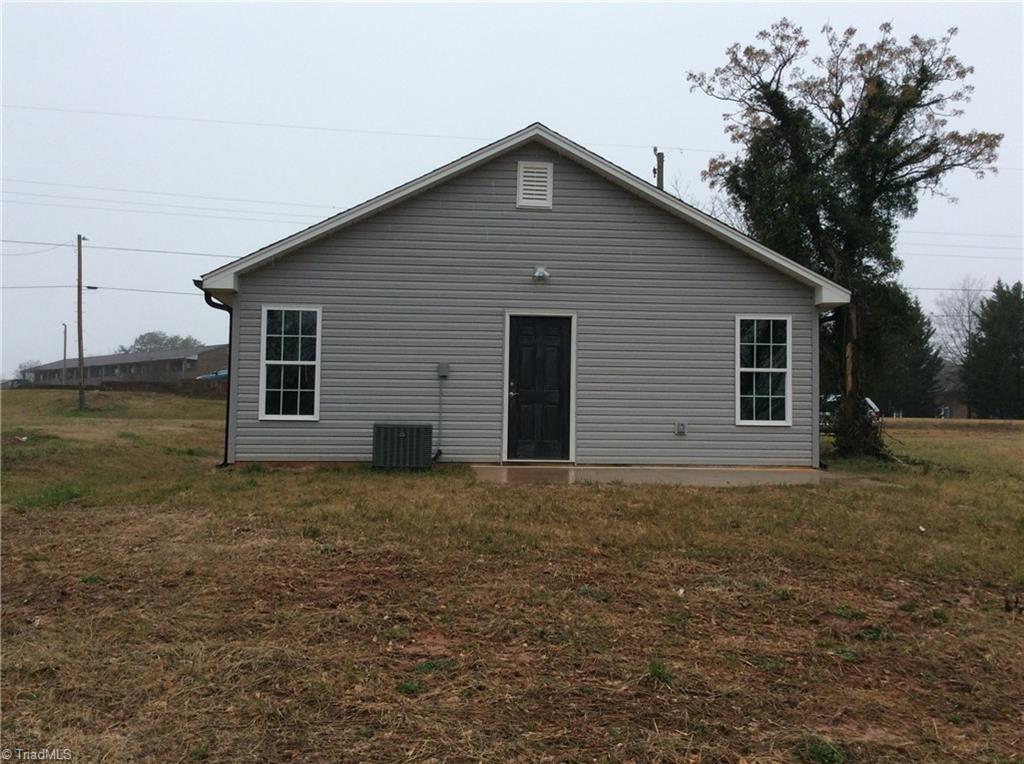 7739 Pine Street Rural Hall, NC 27045 - Photo 14 of 33 Rear View: Here we can see the low maintenance vinyl exterior, thew heat pump and the rear door to a concrete patio where you can sit out and relax after a busy day.