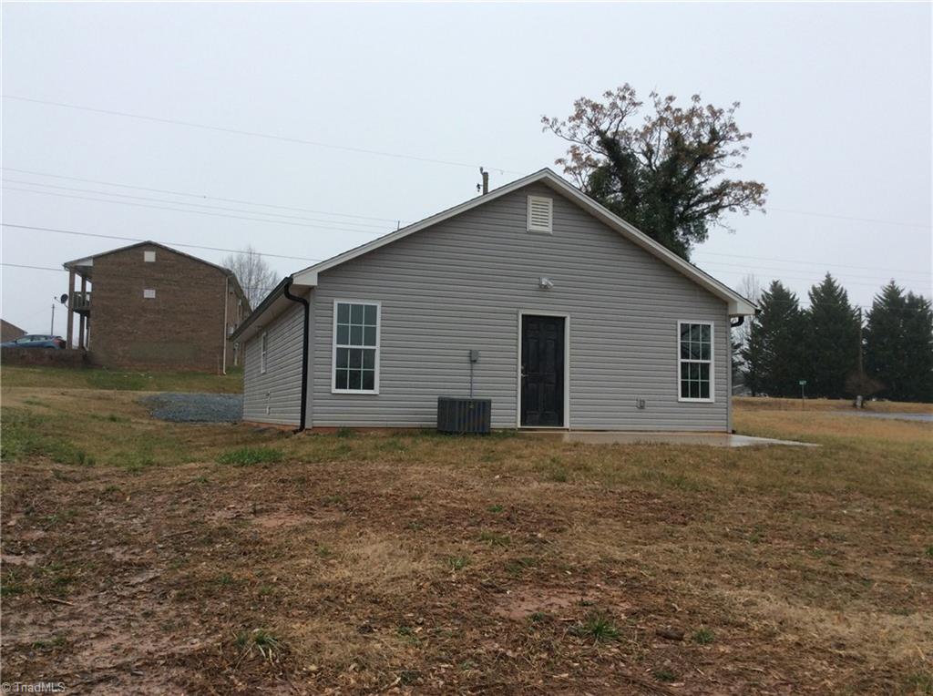 7739 Pine Street Rural Hall, NC 27045 - Photo 15 of 33 Rear Left View: Here we can see the low maintenance vinyl exterior, thew heat pump and the rear door to a concrete patio where you can sit out and relax after a busy day.