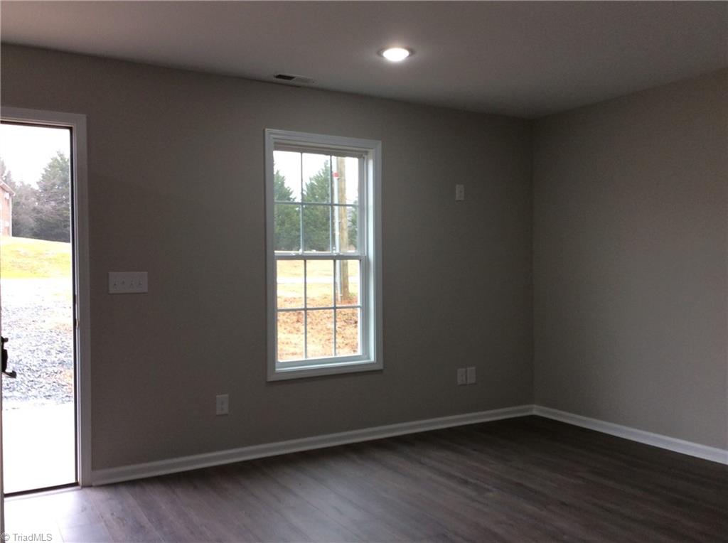 7739 Pine Street Rural Hall, NC 27045 - Photo 18 of 33 Living Room: Features include vinyl plank flooring for easy cleaning, a window for natural lighting, recessed lighting and fresh new paint. The open door is the front entry door.