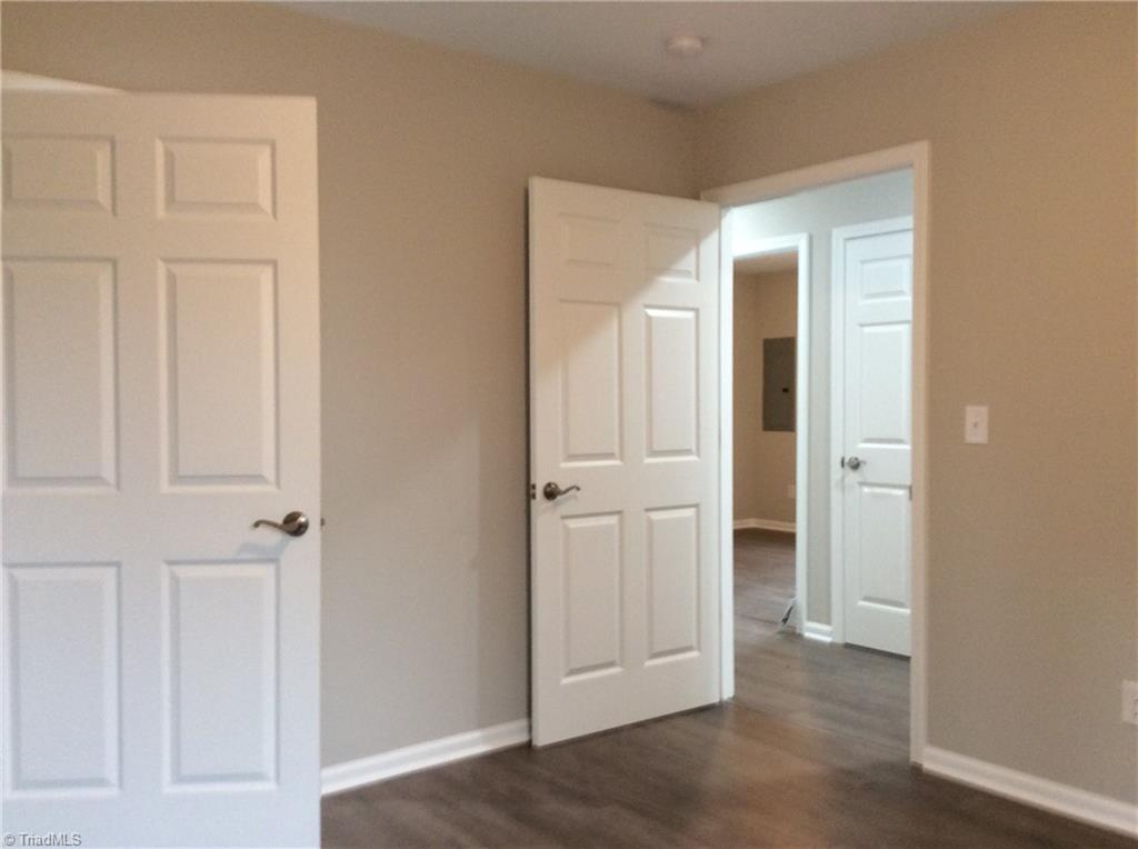 7739 Pine Street Rural Hall, NC 27045 - Photo 5 of 33 Primary Bedroom: Features include vinyl plank flooring for easy cleaning, a window for natural lighting and fresh new paint. The open door on the right side is the entry door from the hallway and the WIC door is on the left side.
