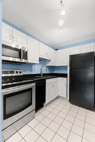 a kitchen with granite countertop a refrigerator and a stove top oven