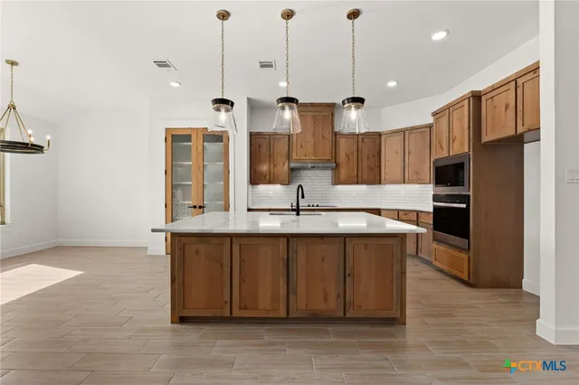 a large kitchen with stainless steel appliances kitchen island granite countertop a sink and a refrigerator