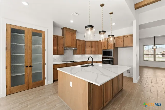 a large kitchen with stainless steel appliances kitchen island a large counter top and a refrigerator