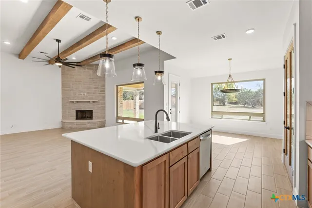 a kitchen with kitchen island a large counter top space a sink stainless steel appliances and cabinets